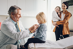 photo of a physician examining a young child in an exam room